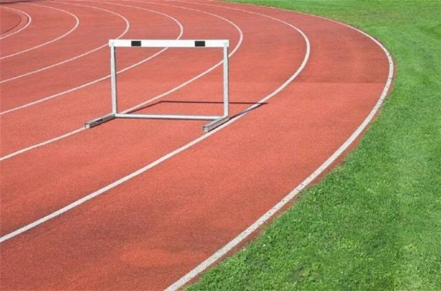Atleta em Pista de Corrida com Pano de Fundo de Pastagem em Competição de Atletismo